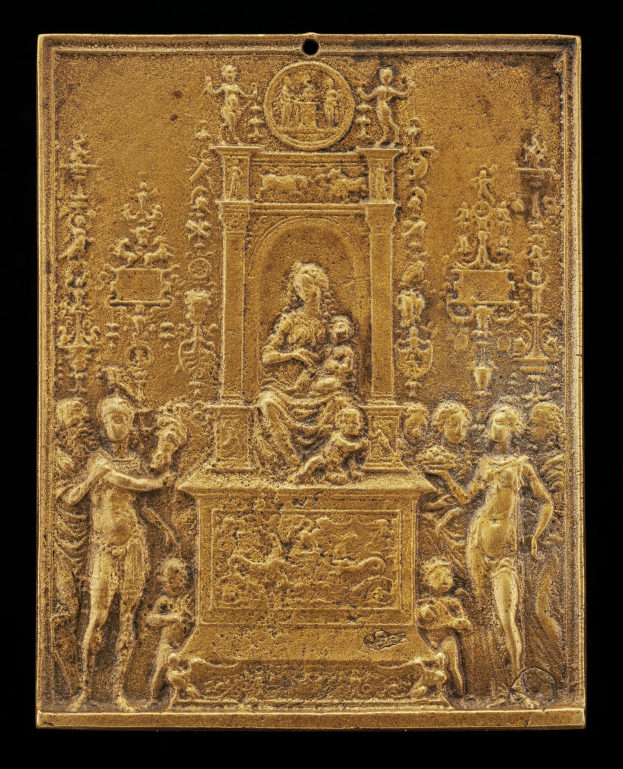 Goldene Plakette mit einer detaillierten Skulptur einer Frau in einem langen Kleid und einem Mann in einem Anzug und Krawatte, eingerahmt von einem prunkvollen goldenen Rand gegen einen schwarzen Hintergrund.