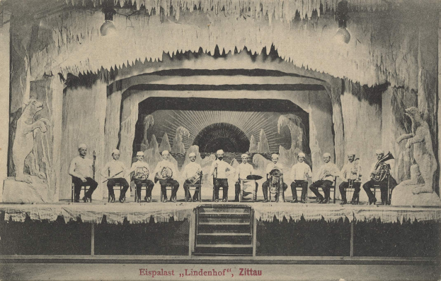 Altes Schwarz-Weiß-Foto einer Gruppe von Menschen auf einer Bühne mit Musikinstrumenten, Treppe hinauf und Skulpturen auf beiden Seiten, beschriftet mit "Lindenhof, Zittau, Deutschland".