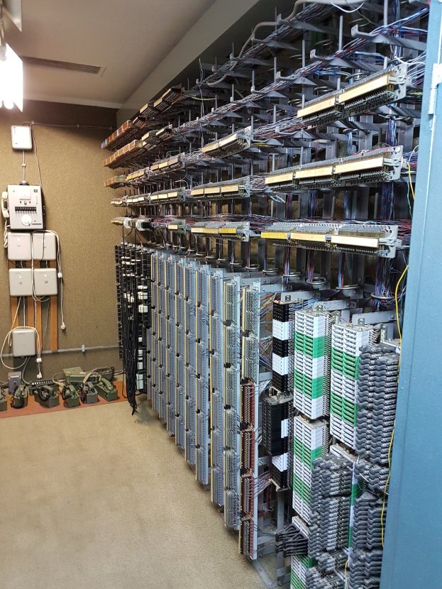 Großer Raum voller numerous wires, elektronische Geräte und Server auf dem Boden, was auf eine Rechenzentrumseinrichtung hindeutet.