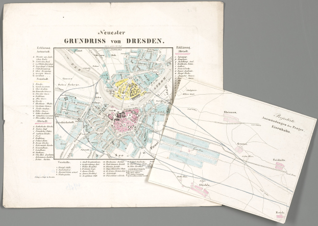 Detailreiche alte Karte von Dresden, Deutschland, mit zwei Papieren im Vordergrund vor einem grauen Hintergrund.