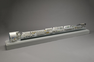 Ein detailliertes Modell des neuen Wasserstoff-Brennstoffzellensystems von Sainsbury's, bestehend aus einem Kraftstofftank, einem Filter, einem Injektor und einer Stromquelle, das auf einer weißen Oberfläche dargestellt ist.