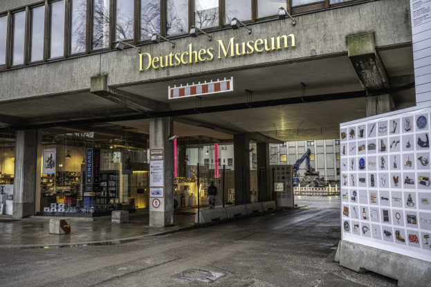 Außenansicht des Deutschen Museums in Berlin, das ein großes Gebäude mit Glasfenstern, Säulen und einer Namensplakette zeigt, sowie eine informative Anzeige auf der rechten Seite.