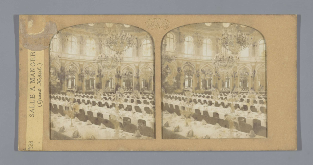 Ein altes Foto eines prächtigen Hotelesszimmers mit Tischen, Stühlen, Kronleuchtern und Fenstern, das ein Schild mit der Aufschrift "Sale à manger, Grand Hotel" links zeigt.