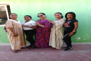 Eine Gruppe von Frauen steht zusammen vor einer grünen Wand mit einem Fenster auf der linken Seite, an einem Internationaler Frauentag-Event teilnehmend.