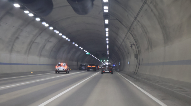 Ein Auto fährt durch einen Tunnel mit Deckenleuchten, beleuchtet von der künstlichen Beleuchtung.