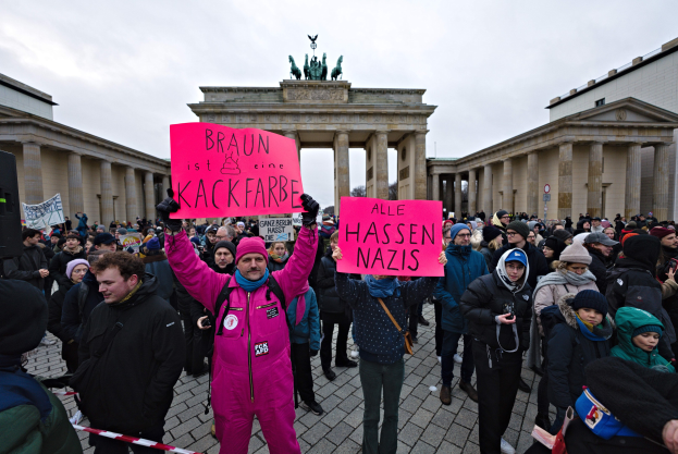 Eine Gruppe von Menschen steht vor dem Reichstag in Berlin, Deutschland, mit Protestschildern gegen die anti-nazistische Bewegung der deutschen Regierung.