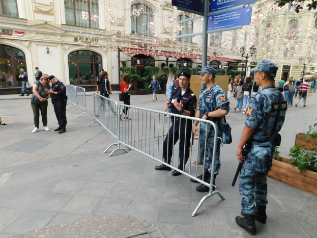 Polizeibeamte in Uniform stehen hinter Absperrungen und blicken auf eine Menge, von denen einige Kappen tragen und Waffen halten, während sie eine Anti-Terror-Operation in Wien, Österreich, durchführen.