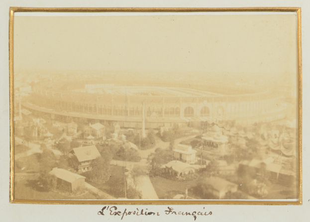 Altes Schwarz-Weiß-Foto eines Stadions umgeben von städtischen Gebäuden, Bäumen und Strommasten mit Text am unteren Rand.