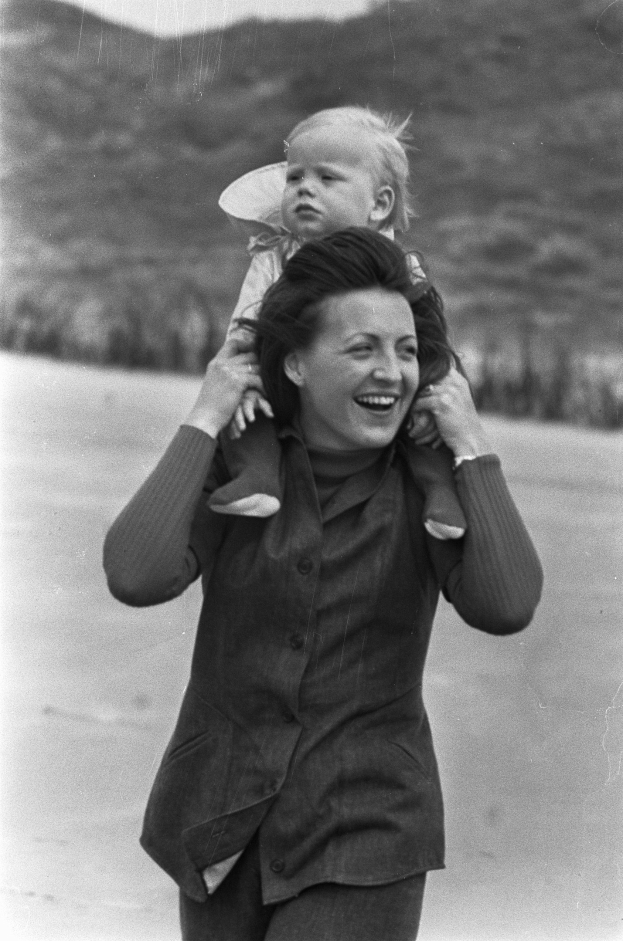 Eine Frau, die glücklich ist und ein Baby im Arm h├Ąlt, mit einem sanft unscharfen Hintergrund, der eine nostalgische Stimmung erzeugen