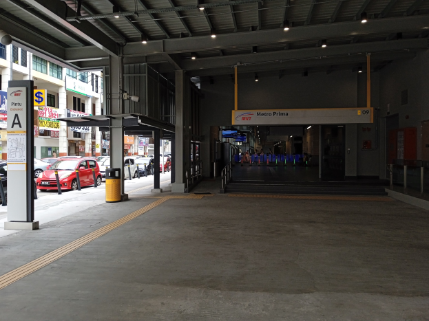 Leeres Parkhaus mit Autos zwischen Betonpfeilern, Deckenbeleuchtung, Informationsschildern an den Wänden und Gebäuden mit Fenstern im Hintergrund.