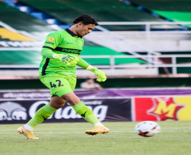 Ein Torwart in grüner Uniform kickt einen Fußball auf einem Rasenfeld in einem Stadion, mit Bannern im Hintergrund, die "Chivas USA gegen Mexico City, 3-1, Copa Libertadores" lesen.