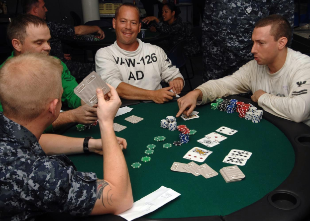 Eine Gruppe von Männern, die um einen Tisch sitzen und Poker mit Münzen und Karten spielen, die vor ihnen ausgebreitet sind.