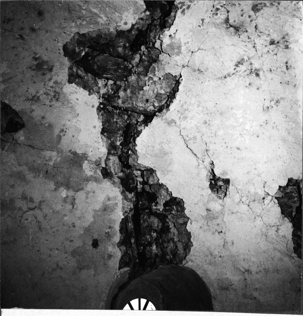 Schwarz-weißes Foto eines Reifens an einer Wand mit einem sichtbaren Riss