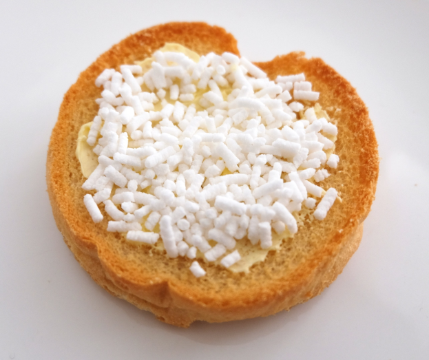 Herzförmiger Brotlaib mit Butter und Zucker auf einer weißen Oberfläche.